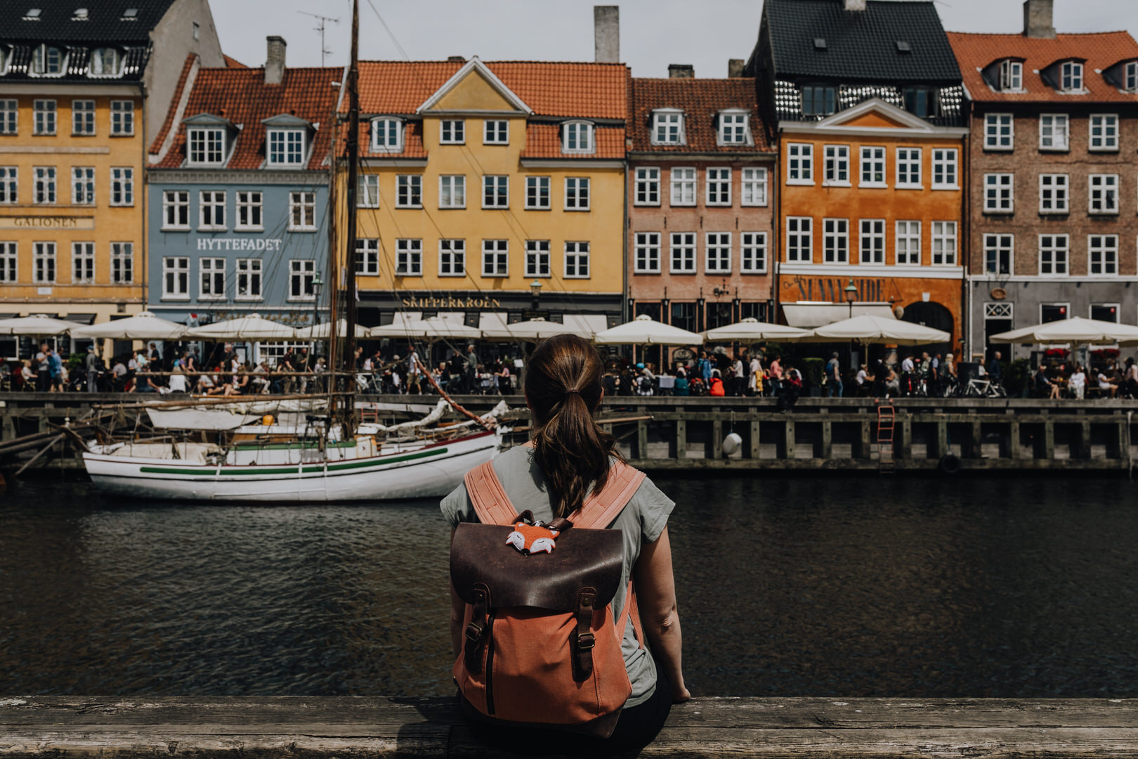 Alexandra mit Rucksack am Hafen in Kopenhagen, bunte Häuser im Hintergrund.