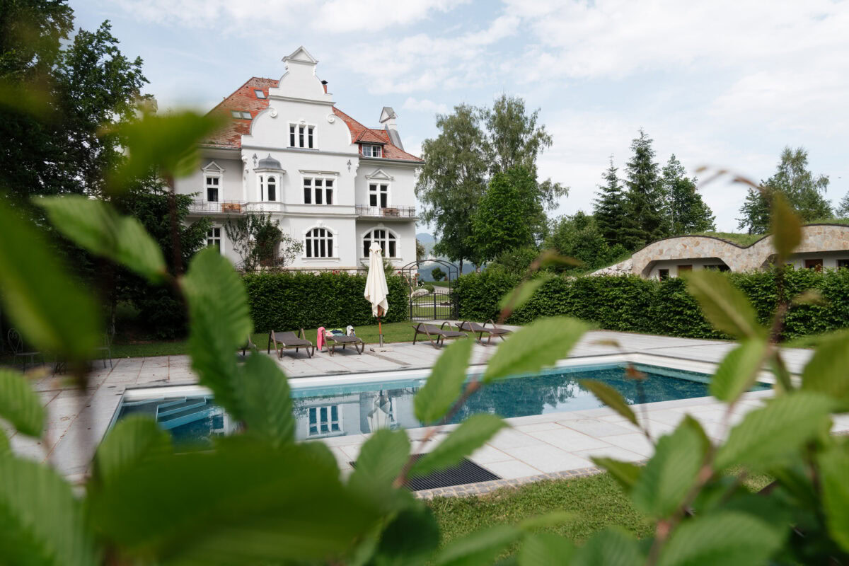 Elegantes Hotel mit Pool, umgeben von Garten und Bäumen in einer ruhigen Lage.
