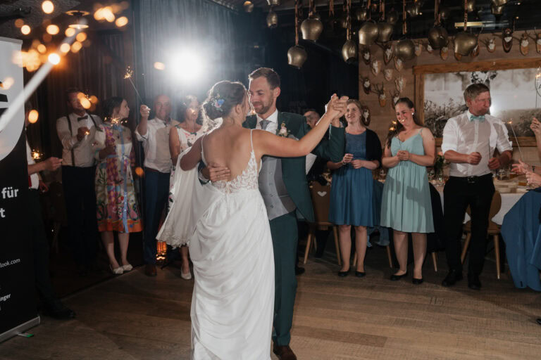 Hochzeit im Sommer: Braut und Bräutigam tanzen bei der Almhochzeit im festlichen Rahmen.